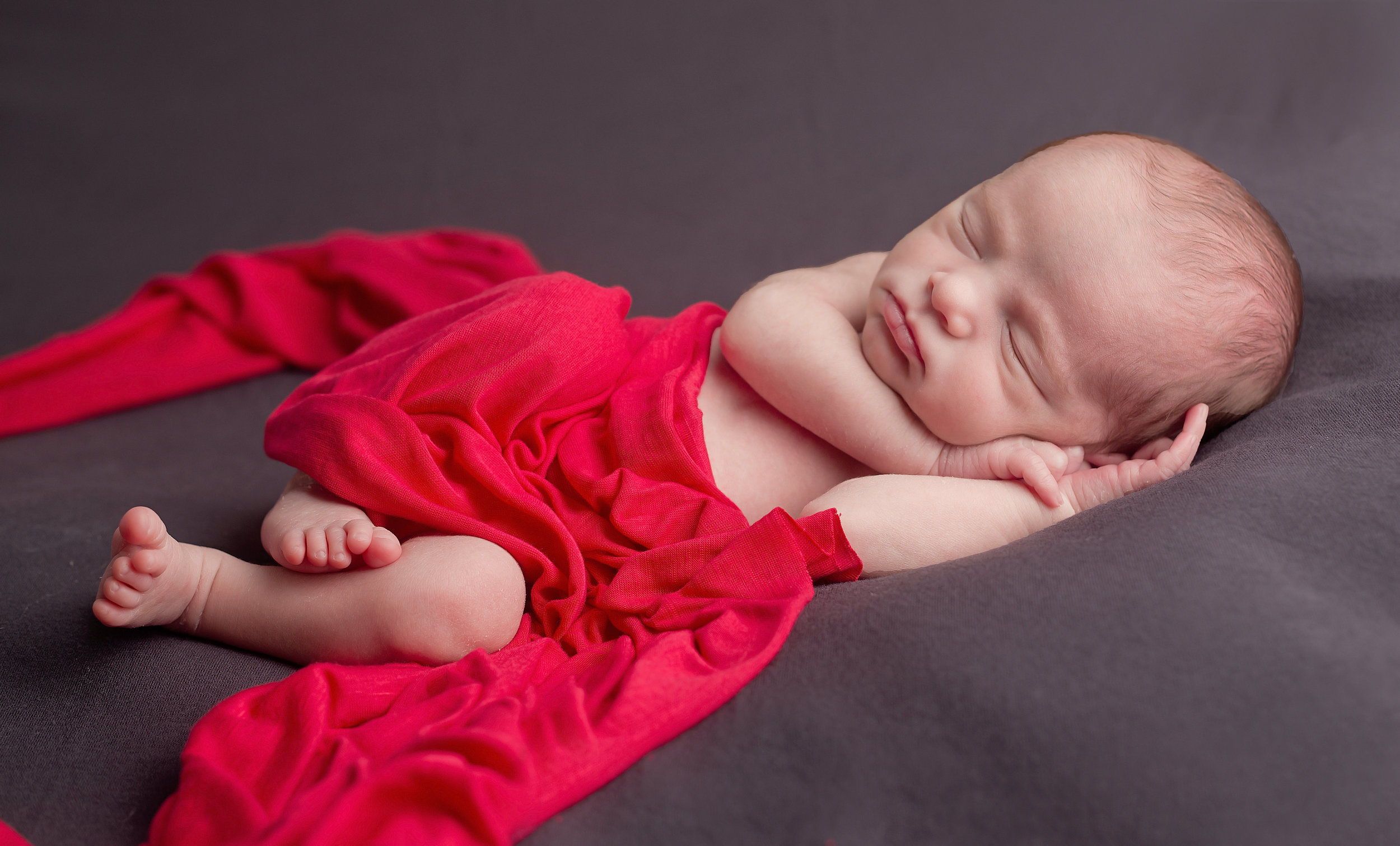 Newborn sleeping with red wrap Nashville Tennessee