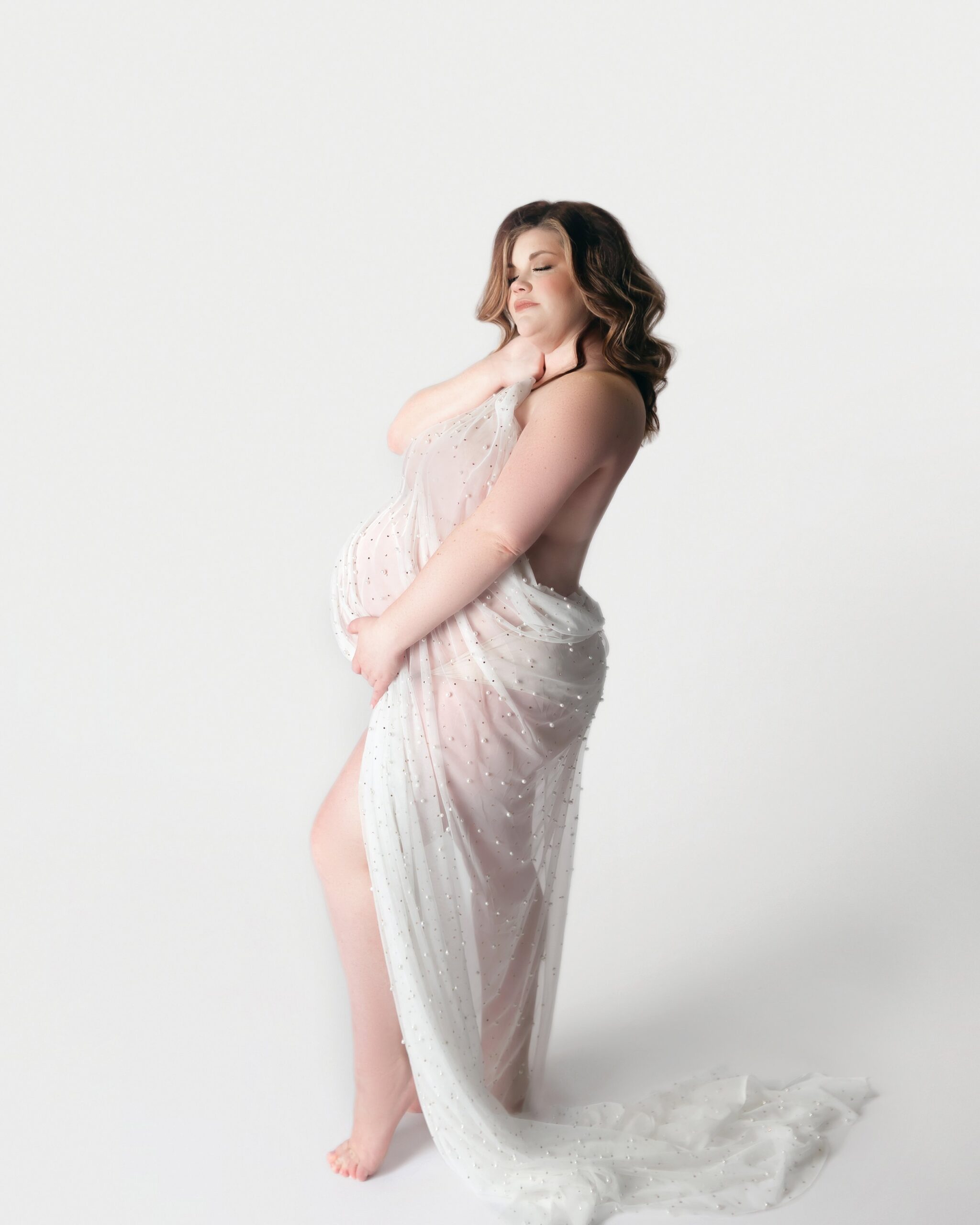 pregnant women with white fabric draped over her belly, during maternity photoshoot in mount juliet tennessee photography studio, near me