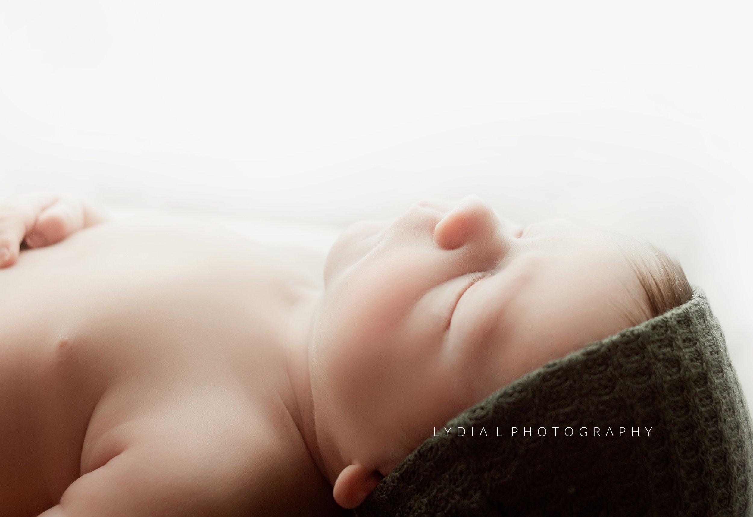baby boy sleeing, wearing little green hat, during newborn photoshoot in brentwood tennessee photography studio near me