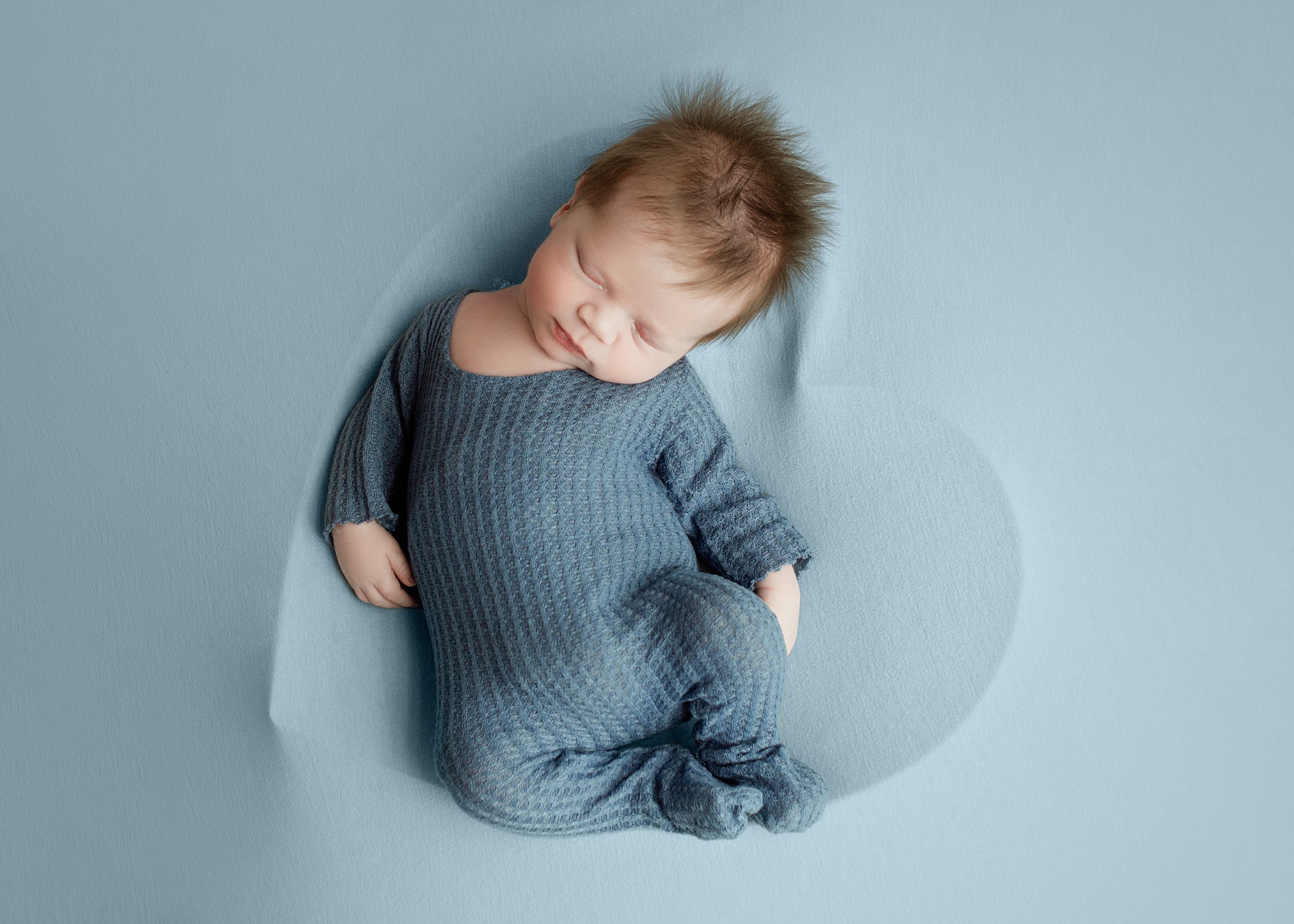 baby boy, wearing blue sleeper, during newborn photoshoot, in brentwood tennessee photography studio