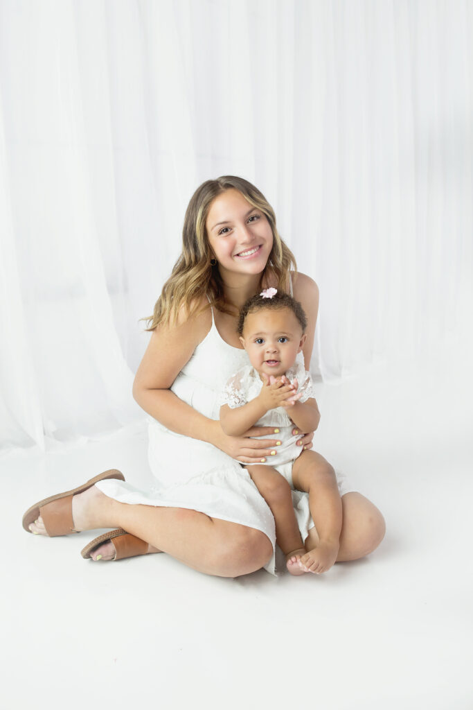 Older sister holding baby sister during family photoshoot in Franklin Tennessee photography studio 