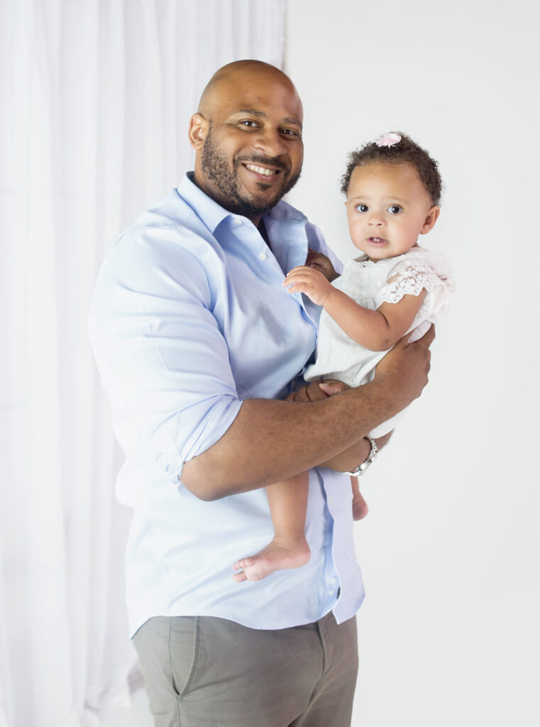 Dad hugging daughter during first birthday cake smash photoshoot in Mount Juliet Tennessee Photography studio  