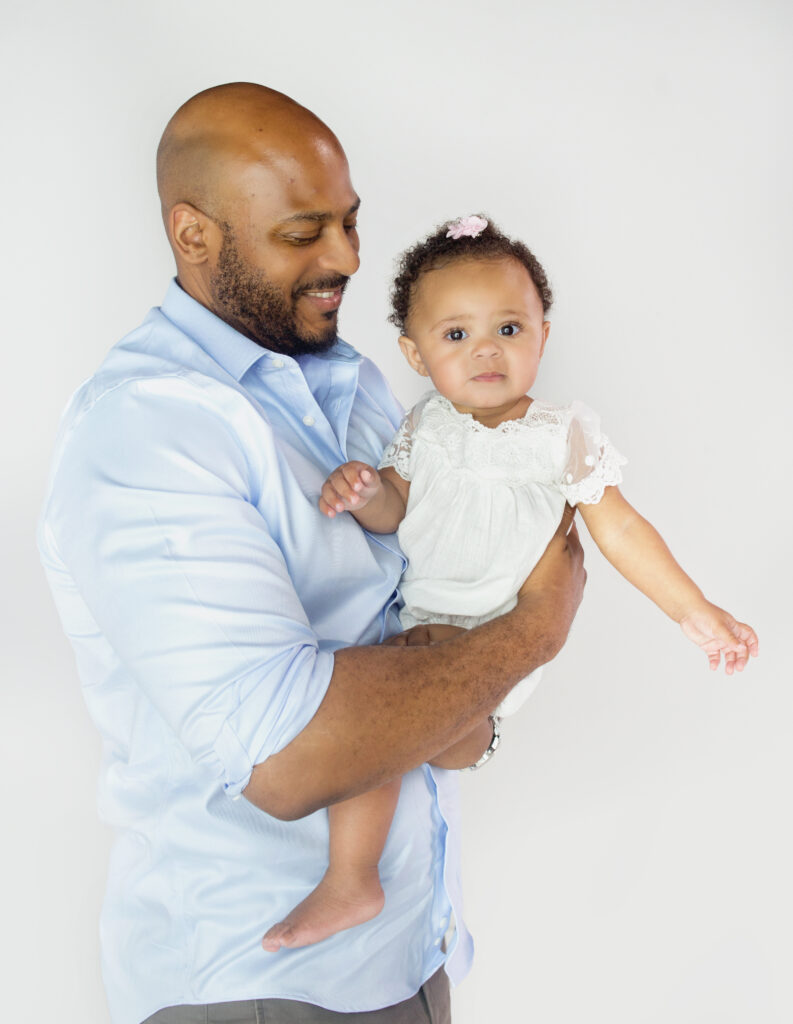 Dad laughing with daughter during first birthday cake smash photoshoot in Mount Juliet Tennessee photography studio