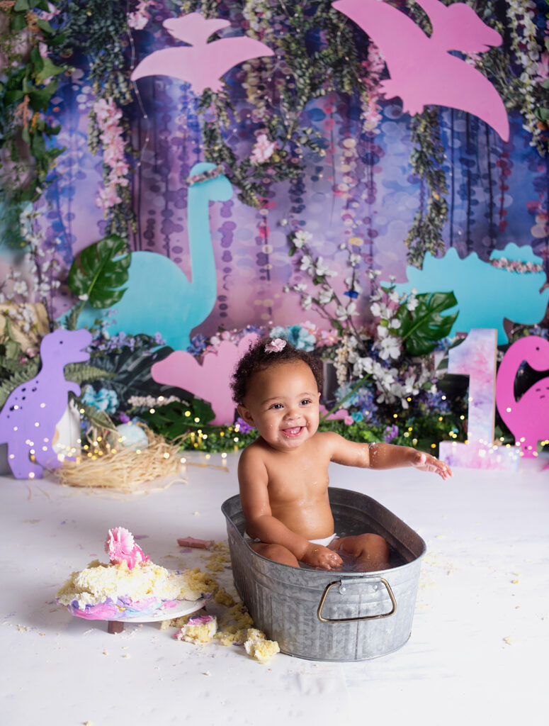 Baby girl laughing with a cake in a little tub during cake smash photoshoot in Mount Juliet Tennessee photography studio.