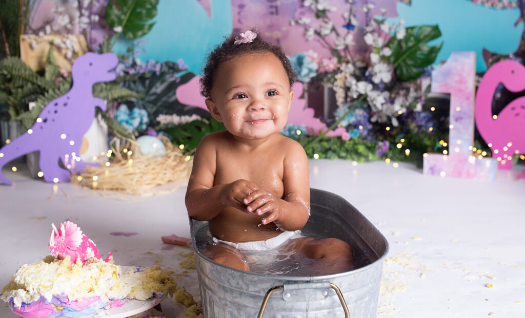 Close up photo of little girl smiling in little tub during first birthday cake smash photoshoot in Mount Juliet Tennessee photography studio 