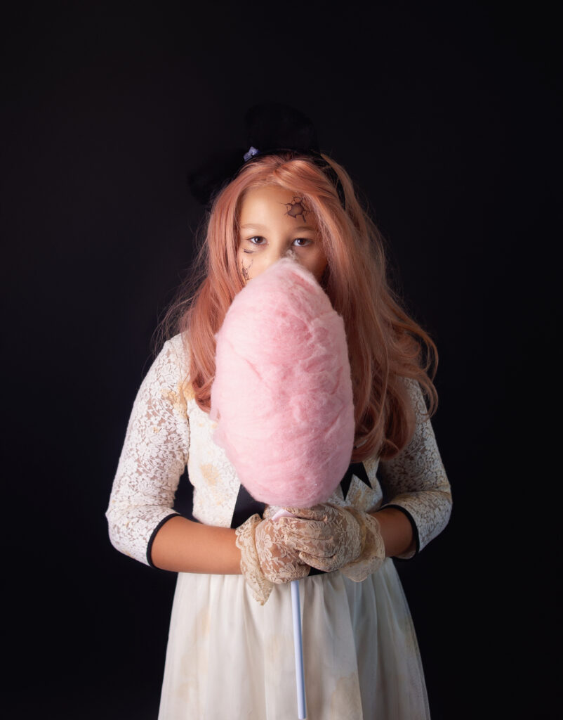 Young girl dressed as creepy doll holding cotton candy during Halloween mini session photoshoot with Nashville, TN Photographer 