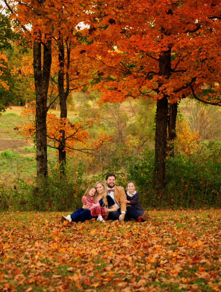 Family posing in the fall leaves for a fall mini session photoshoot with Nashville, TN photographer 